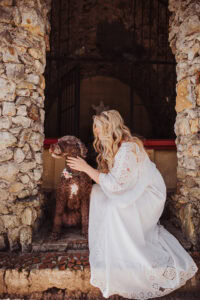 dow wearing flower crown around neck and pregnant blonde woman in white gown in stone temple
