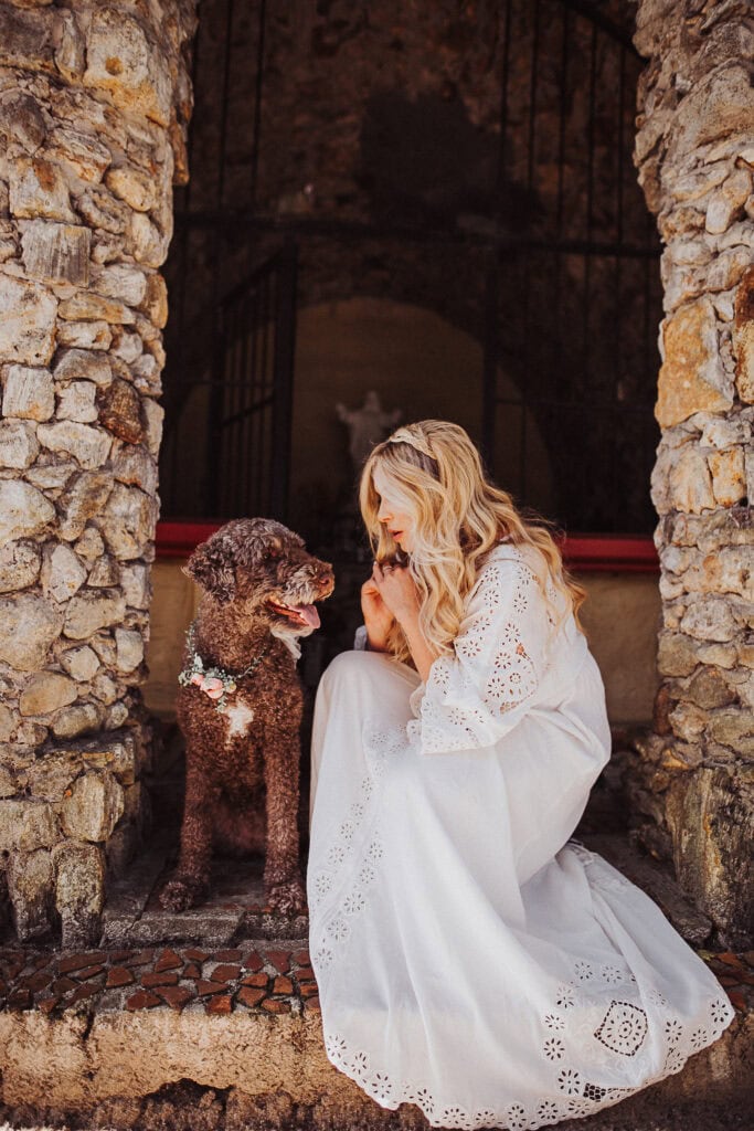 dow wearing flower crown around neck and pregnant blonde woman in white gown in stone temple