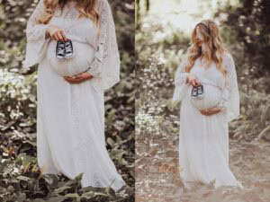 Pregnant woman in white lace maternity gown holding baby shoes in lush green forest, intimate maternity session location with natural canopy lighting